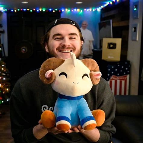 A Man Is Holding A Stuffed Animal In His Hands And Smiling At The Camera