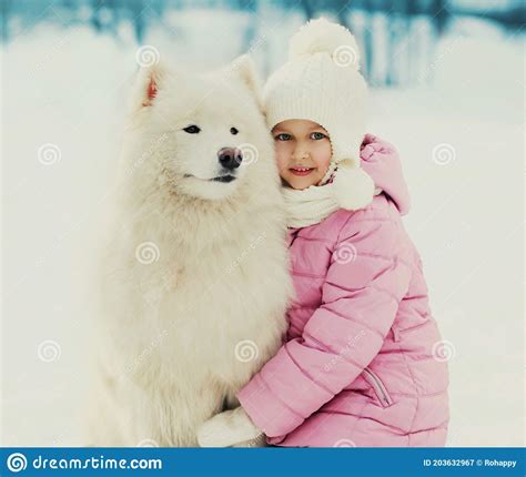 Child With White Samoyed Dog Walking In Snowy Winter Stock Image