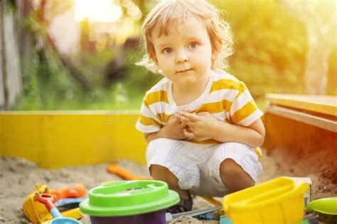 A Little Boy Playing In The Sandbox At The Playground Outdoors Stock
