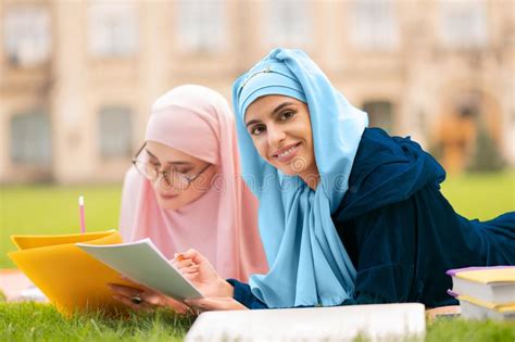 Student Wearing Blue Hijab Holding Orange Tablet Sitting Near Friend