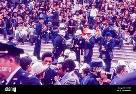 Police Officers Carry Off Protesters In Hippie Attire From A Large