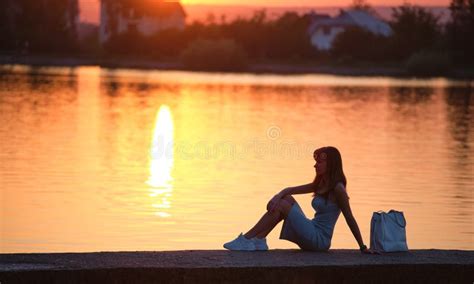 Lonely Woman Sitting On Lake Side On Warm Evening Solitude And