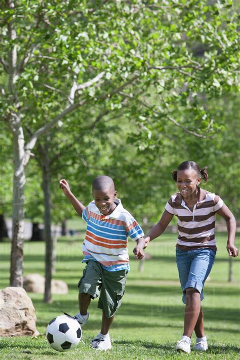 African American Children Playing Soccer In Park Stock Photo Dissolve
