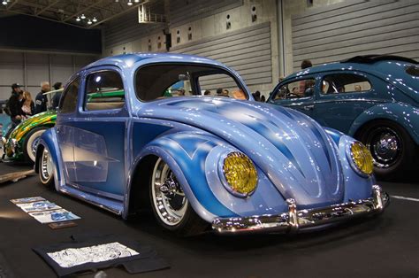 An Old Blue Vw Bug Is On Display In A Showroom With Other Cars