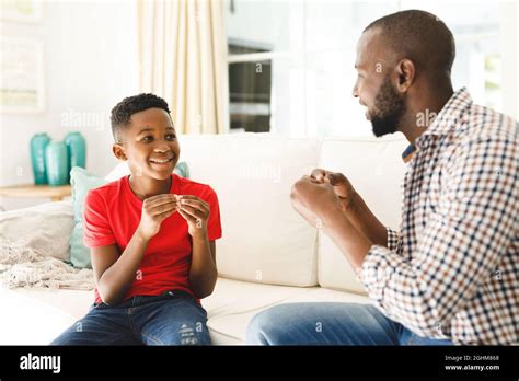 Happy African American Father With Son Sitting On Couch In Living Room