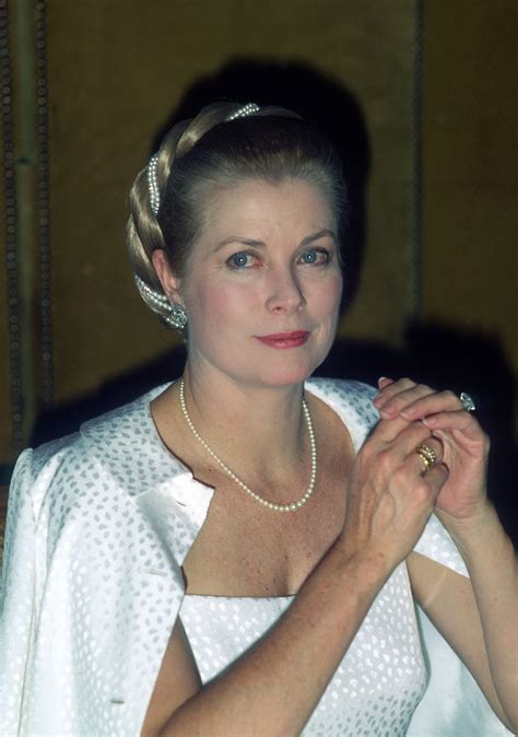 An Older Woman Wearing A White Dress And Pearls In Her Hair Is Posing