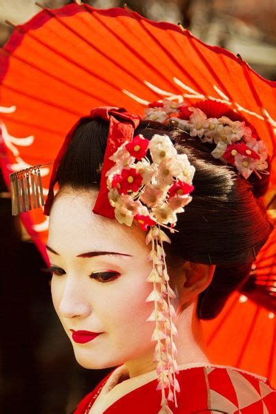 a geisha woman in traditional japanese dress holding an umbrella and looking off to the side