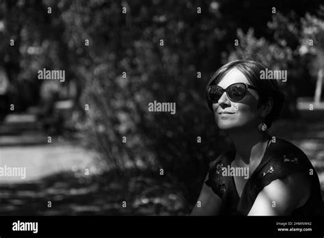 portrait of a white 30 year old woman sitting with her face in the sun in the shadows of the