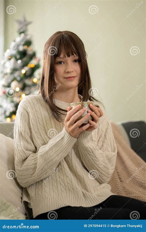 A Beautiful Caucasian Woman Is Enjoying Her Coffee On A Couch In Her Living Room On Christmas