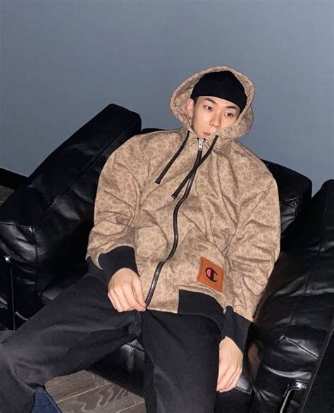 A Man Sitting On Top Of A Black Couch Wearing A Hoodie And Sweatpants