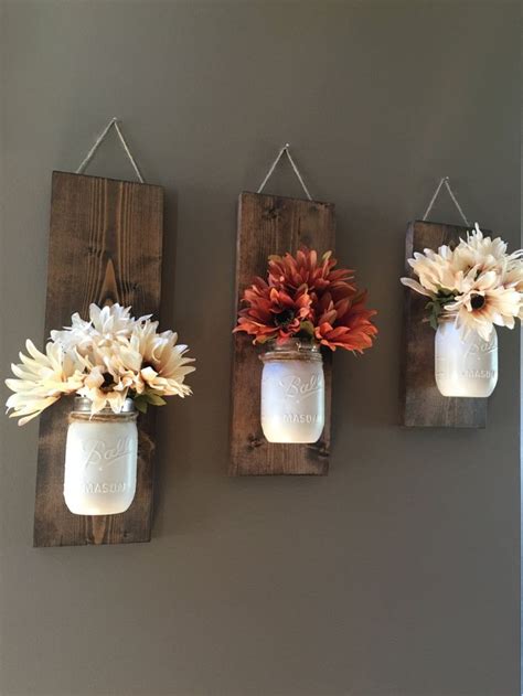 Three Mason Jars With Flowers Hanging On The Wall