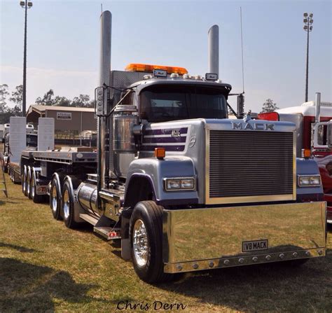 A Large Semi Truck Parked On Top Of A Grass Covered Field Next To Other