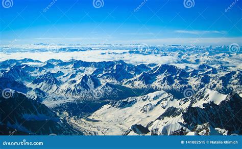 Snow Capped Mountain Peaks Against A Bright Blue Sky The Concept Of