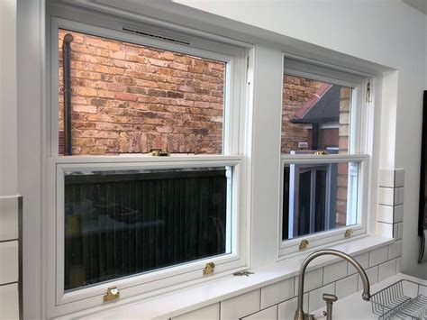A Kitchen With Three Windows And A Sink In Front Of The Window Is Brick