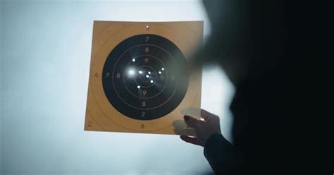 Woman Inspecting Bullet Holes In Paper Shooting Target Industrial