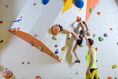 Rock Climbers In Bouldering Gym Climbing Up Overhanging Wall Stock