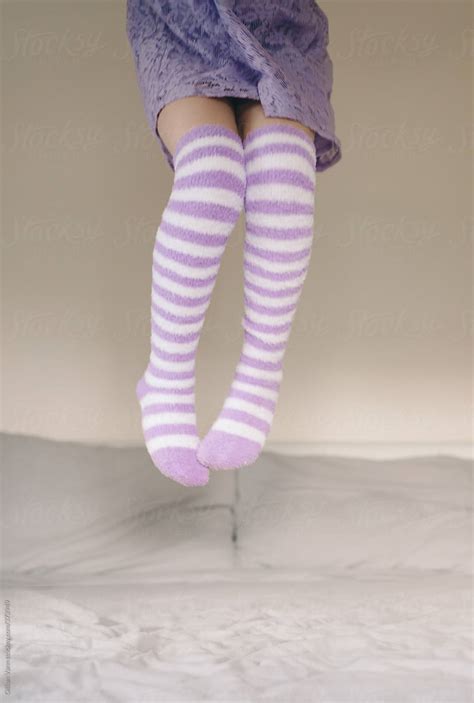 Girl Jumping On The Bed In Purple Stripey Socks Del Colaborador De Stocksy Gillian Vann
