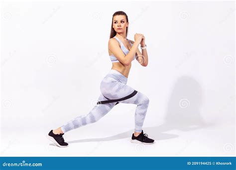 side view full length assertive concentrated woman gymnast in white top and tights doing fitness