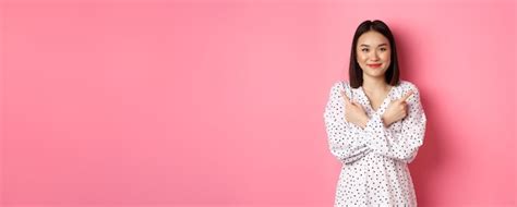 쇼핑 Sm에 두 가지 변형을 보여주는 옆으로 손가락을 가리키는 낭만적인 드레스에 아름 다운 아시아 소녀 프리미엄 사진