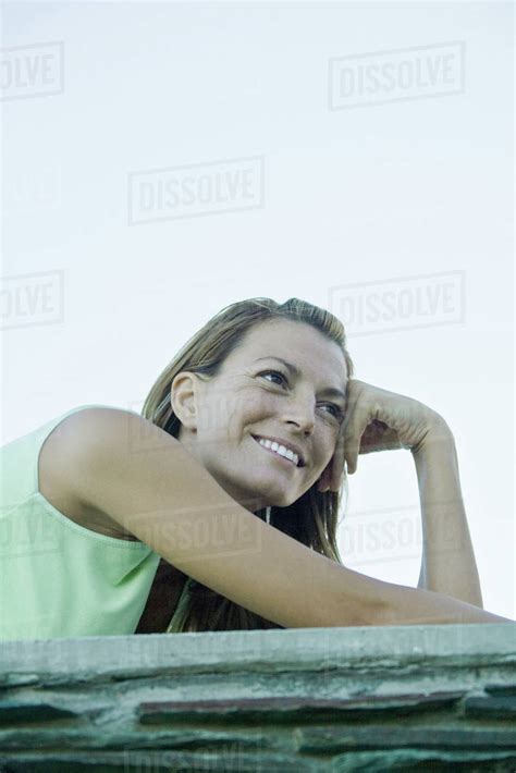 Woman Smiling Leaning Head Against Hand And Looking Away Low Angle View Stock Photo Dissolve