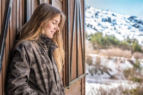 retrato joven mujer bonita en invierno en una cabaña de troncos en la nieve foto premium