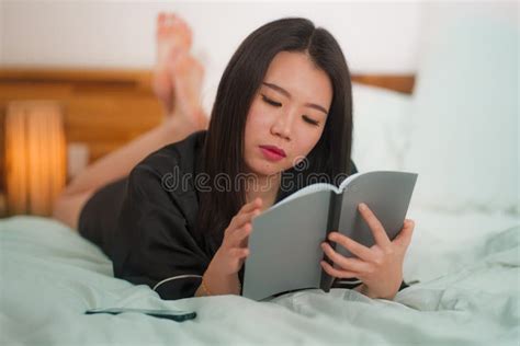 Young Beautiful And Sweet Asian Korean Woman In Bed Reading Book Novel