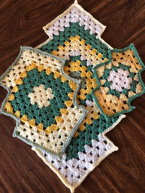 Three Crocheted Squares Sitting On Top Of A Wooden Table
