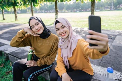 Two Girls Wearing Hijab Smiling And Holding A Smartphone When Selfie