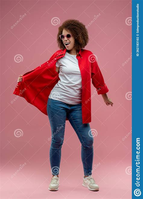 Pretty Curly Haired Woman In Red Jacket And Sunglasses Posing Stock