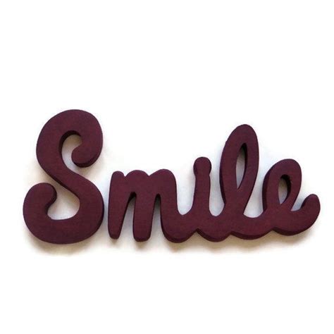 The Word Smile Is Made Out Of Wood And Sits On Top Of A White Surface