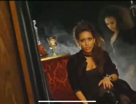 a woman sitting on a red chair in front of a painting with other women