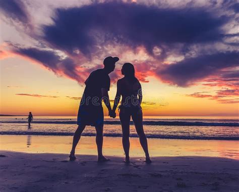 Silhouettes Of Couple In Love Kissing At Beach Sunset Celebrating