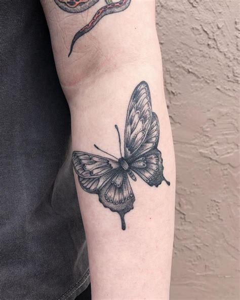 A Black And White Butterfly Tattoo On The Left Arm With A Snake In The
