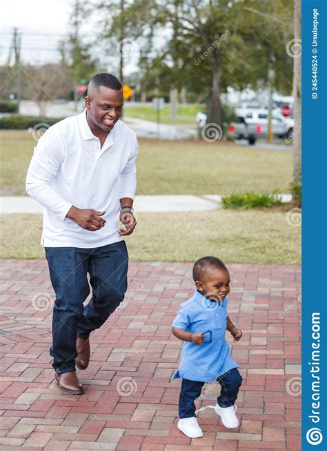 A Dad Chasing His Toddler Son Around Outdoors While They Are Playing