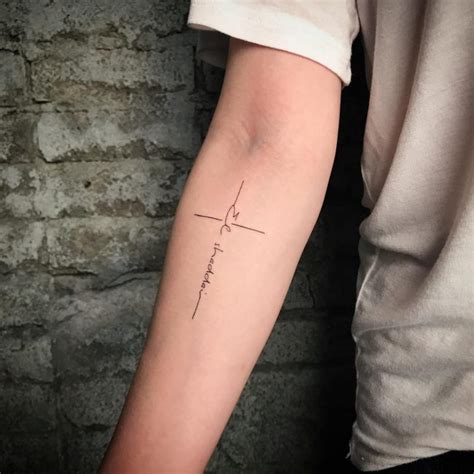 Black Simple Cross With Message Tattoo On Inner Lower Arm