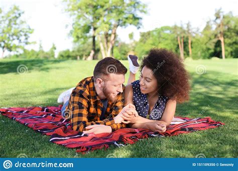 Young Loving Interracial Couple Resting In Park On Spring Day Stock