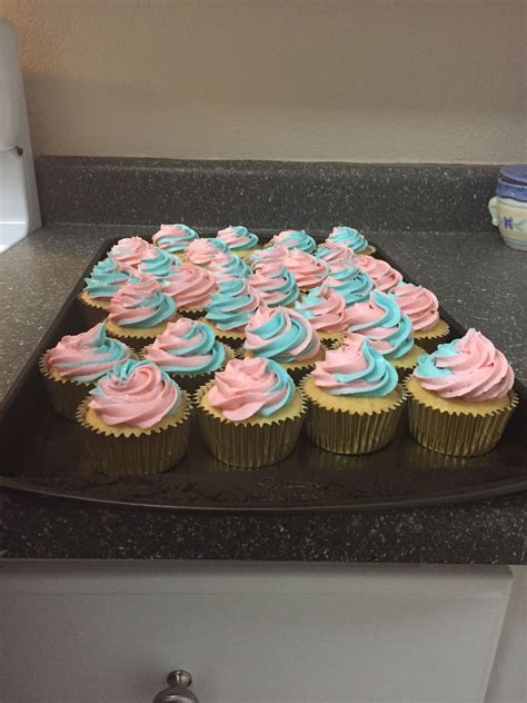 cupcakes with blue and pink frosting are on a black tray in the kitchen
