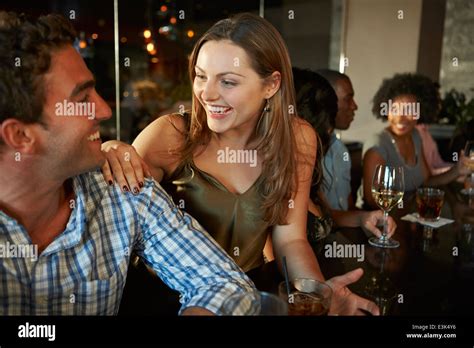 Couple Enjoying Drink At Bar With Friends Stock Photo Alamy