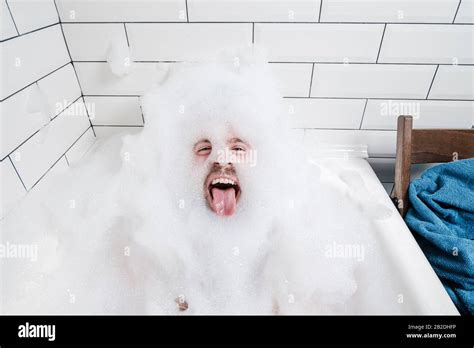 Funny Positive Man Lies In A Bathtub With Lush Foam And Shows His