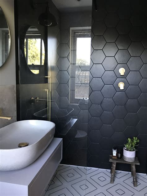 A Black And White Bathroom With Hexagonal Tiles On The Wall Sink And