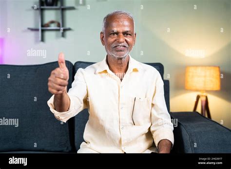 Indian Senior Old Man Showing Thumbs Up Sign Or Hand Gesture By Looking At Camera At Home