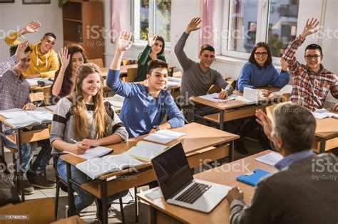 Happy High School Students Raising Their Hands On A Class Stock Photo
