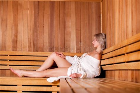 Beautiful Woman Sitting Relaxed In A Wooden Sauna White Coat Stock