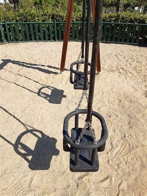 Side View Of Double Swing Bench With Metal Ropes On Sand Ground Of