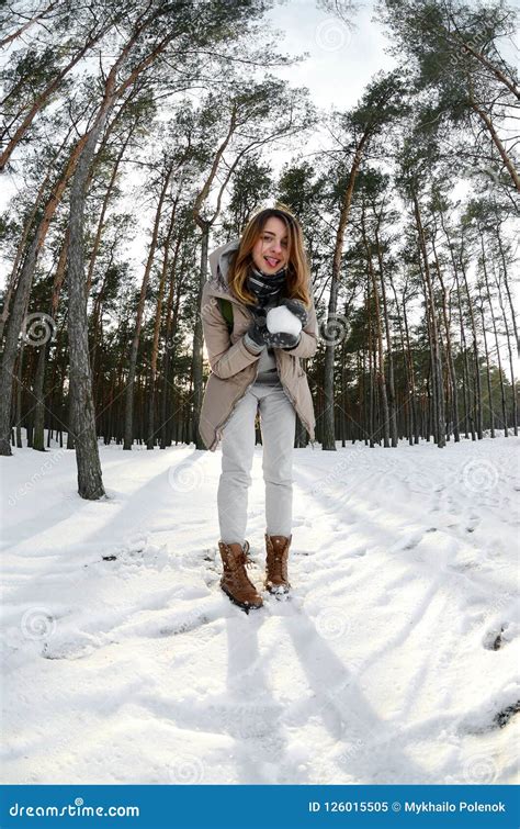 A Young And Joyful Caucasian Girl In A Brown Coat Holds A Snowball In A