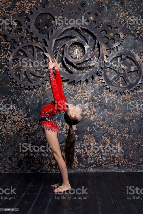 Girl Gymnast In A Red Suit With Sparkles Doing Exercise Is Standing On