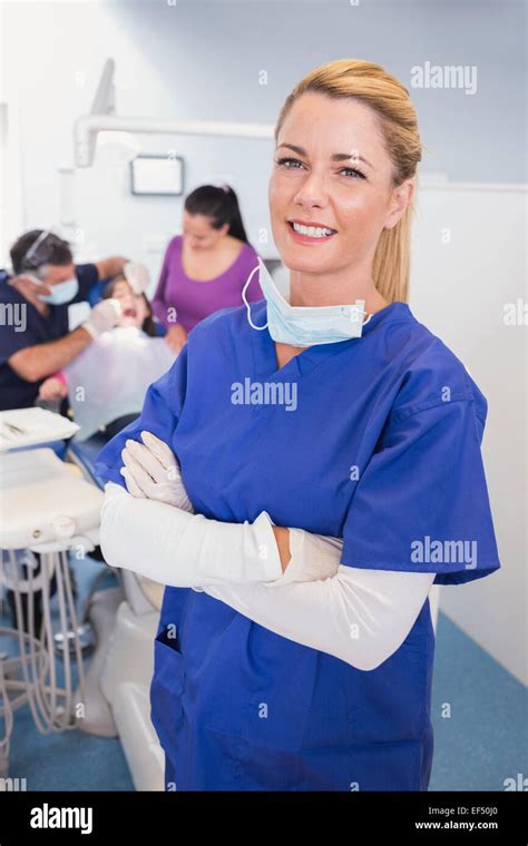 Nurse With Folded Arms With Patient And Dentist Behind Her Stock Photo