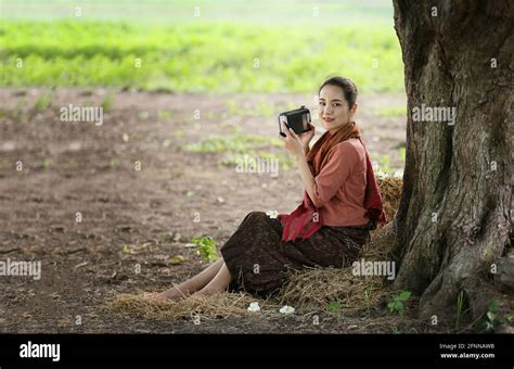 asian woman wearing traditional thai culture in field vintage style listening radio on buffalo