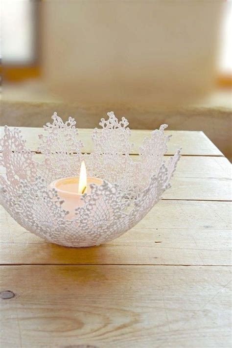 A Lit Candle Sitting On Top Of A Wooden Table Next To A Lace Doily Bowl