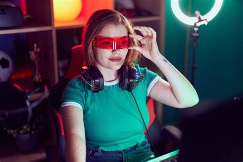 Young Redhead Woman Streamer Playing Video Game Using Virtual Reality Glasses At Gaming Room